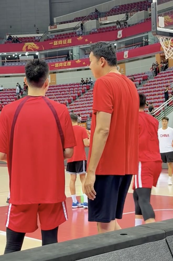 王治郅身穿中国男篮红色T恤，进到场地协助队友们进行热身训练